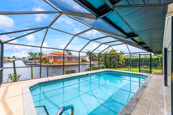 Une piscine avec vue sur un canal et une maison située de l’autre côté.