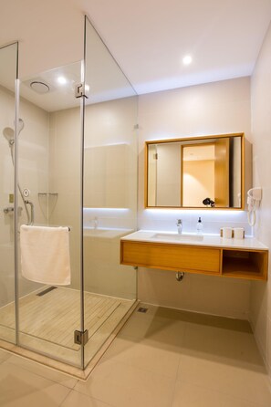 A modern bathroom with a glass shower enclosure, a wooden vanity, and a large mirror. - Ji Hotel (Shanghai)