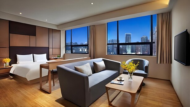 A modern hotel room with a large bed, a sofa, a coffee table, and a TV. - Ji Hotel (Shanghai)