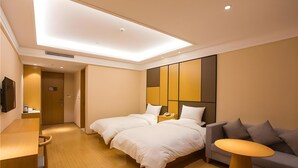 A hotel room with two beds, a sofa, a small table, and a TV on the wall. - Ji Hotel (Shanghai)