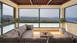 Ein Balkon mit einer Couch, einem Couchtisch mit Früchten und Getränken sowie zwei Blumentöpfen.