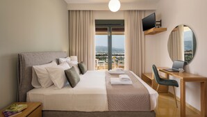 Ein Hotelzimmer mit einem großen Bett, einem Schreibtisch mit einem Laptop, einem Fernseher und Blick auf die Stadt.