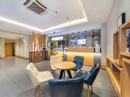 Interior moderno de cafetería con mostrador de recepción, zona de estar y una máquina de café.