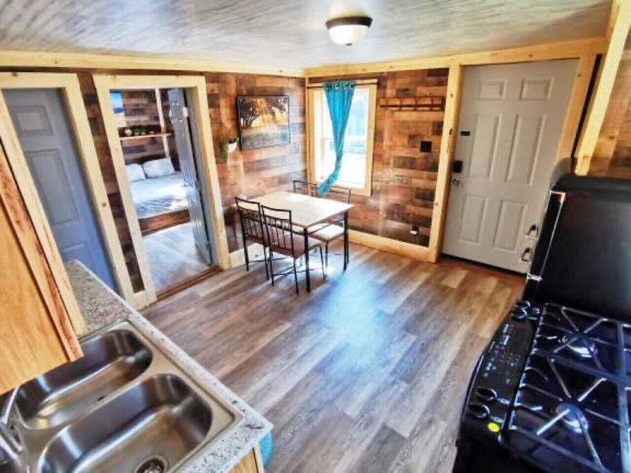 A compact kitchen with a dining area, wooden walls, and a stove.