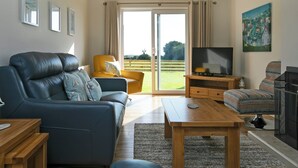 En stue med sofa, lænestol, fjernsyn og et billede på væggen.