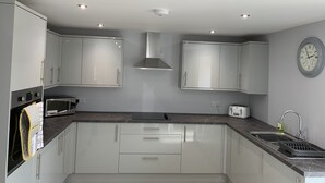A modern kitchen with white cabinets, a microwave, a toaster, and a sink. - Immaculate cosy comfortable home, central location (Inverbervie)