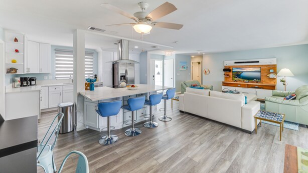 A modern kitchen with a central island, bar stools, and a ceiling fan. - On the River and oh that view! (Cape Coral)