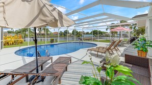 A poolside area with lounge chairs, a covered seating area, and a view of a lake. - On the River and oh that view! (Cape Coral)
