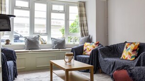 Una sala de estar acogedora con un conjunto de sofás, una mesa de centro y un ventanal con cortinas.