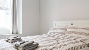 Una cama bien hecha con ropa de cama a rayas y toallas dobladas al lado.