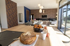Een moderne keuken met een grote houten tafel, een brood en een koffiekop.