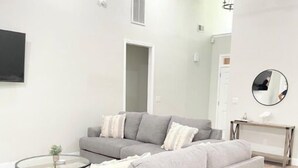 Un soggiorno moderno con un divano modulare grigio, un tavolino in vetro e una ventola a soffitto.