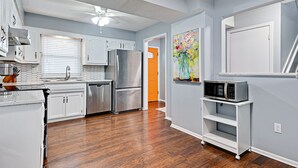 Una cocina moderna con armarios blancos, electrodomésticos de acero inoxidable y suelo de madera.