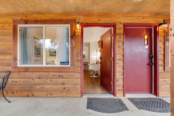 A wooden cabin with two numbered doors, a window, and a chair outside. - Quilcene ground-floor studio with mountain views & fast WiFi - dog-friendly (Quilcene)