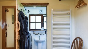 Een badkamer met een wastafel, toilet, handdoekhouder, houten stoel en radiator.