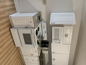 Une cuisine avec des meubles blancs, un four à micro-ondes, une cuisinière et un réfrigérateur.