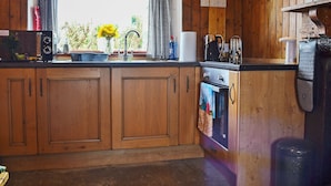 A wooden kitchen with a window, sink, and oven. - Mains of Auchmedden Cottage (Near Pennan)