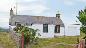 A white house with a grey roof, a chimney, and a garage. - Mains of Auchmedden Cottage (Near Pennan)