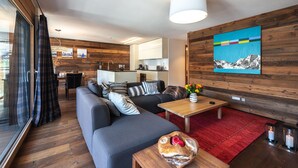 A modern living room with a grey sofa, wooden flooring, a red rug, and a wooden coffee table. - Luxurious Chalet Petit - matterhorn views, central location, outdoor hot tub (Zermatt)