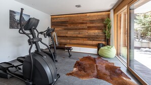 A modern gym with two elliptical machines, a green bean bag, and a large leather rug on the floor. - Luxurious Chalet Petit - matterhorn views, central location, outdoor hot tub (Zermatt)