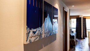 A hallway with a large wall-mounted artwork depicting a mountain scene. - Luxurious Chalet Petit - matterhorn views, central location, outdoor hot tub (Zermatt)