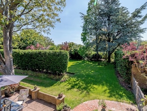 A well-maintained garden with a patio area, a lawn, and various plants.