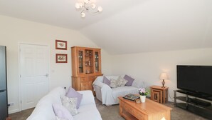 A living room with a sofa, a wooden cabinet, a TV, and a lamp. - The Cider Shed (Winscombe)