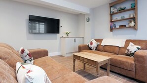 A living room with a sofa set, a coffee table, a flat-screen TV, a bookshelf, and a clock on the wall. - 2 bedroom accommodation in Duke Street (Duke Street)
