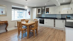 A modern kitchen with white cabinets, a dining table with chairs, and a built-in oven. - 2 bedroom accommodation in Duke Street (Duke Street)