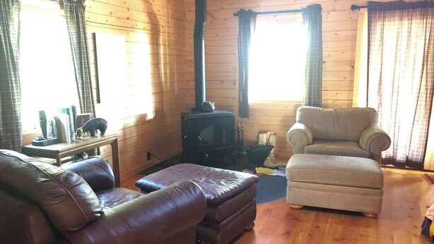A cozy living room with a fireplace, leather sofas, and a wooden floor. - Beautiful Mountain Cabin near Tetons Yellowstone (Dubois)