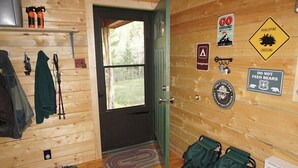 Interior d'una cabana de fusta amb una porta, un finestral i diversos senyals, incloent un avis de pas d'animals.