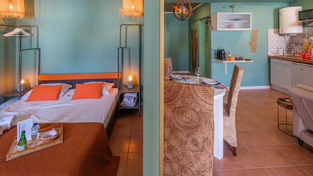 Une chambre d’hôtel avec un lit, une table de chevet, un plateau avec des boissons et un luminaire suspendu.