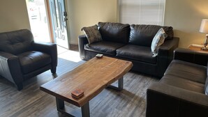 Un salon avec un canapé en cuir foncé, une table basse en bois et un fauteuil en cuir noir.