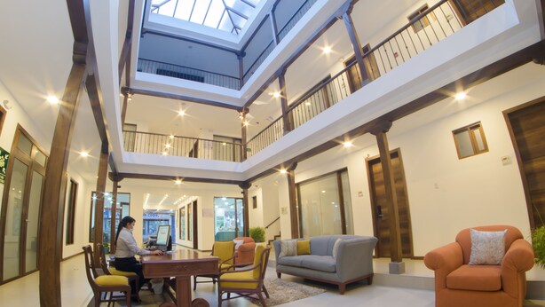 A spacious interior with a high ceiling, a central open area with seating, and a staircase connecting multiple levels. - REEC Latacunga by Oro Verde Hotels (Latacunga)