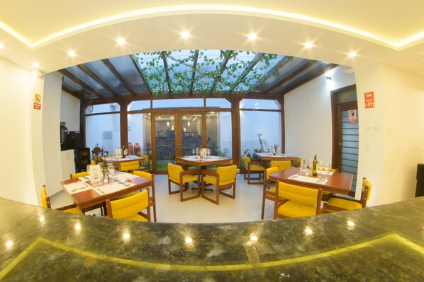 Un restaurante con sillas y mesas amarillas, un recinto de vidrio y vistas al exterior.