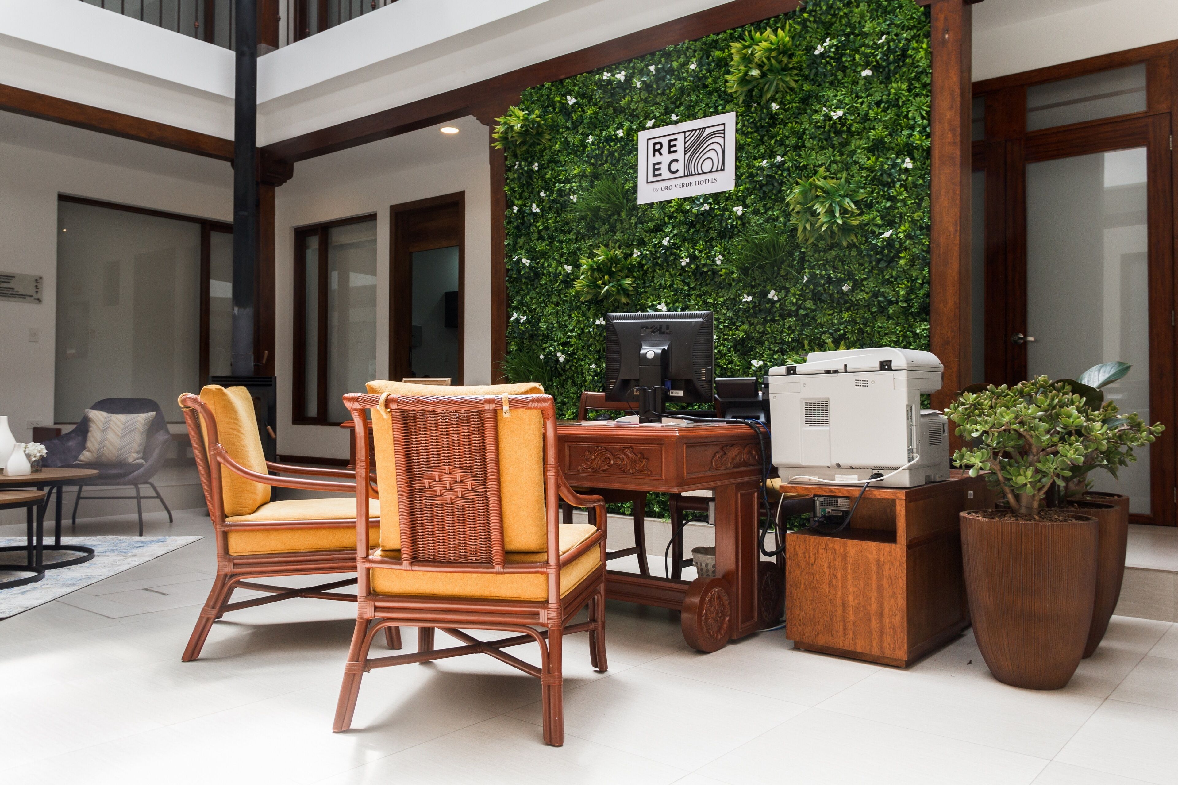A reception area with wicker chairs, a wooden desk, and a computer.