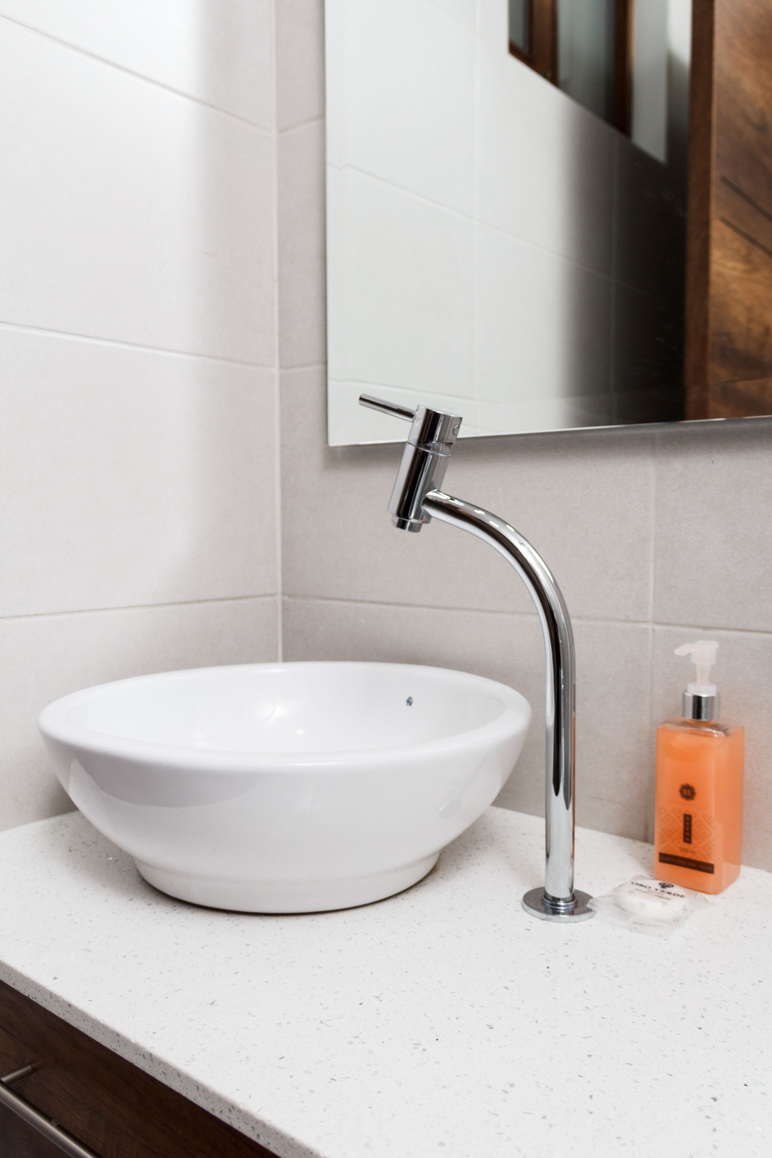 Une salle de bain avec un lavabo blanc, un robinet chromé et un miroir au-dessus.