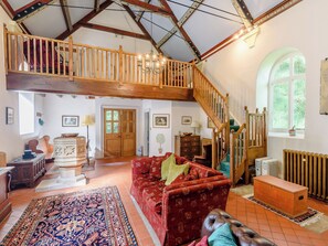 A spacious living room with a high ceiling, wooden staircase, and a large window. - 2 bedroom accommodation in Panton (Panton)