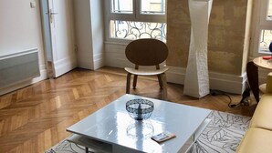 Ein modernes Wohnzimmer mit einem weißen Couchtisch, einem Holzsessel und einem gemusterten Teppich.