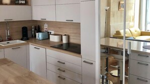 Eine moderne Küche mit weißen Schränken, einer Holztischplatte und einem Essbereich mit einem gelben Sofa.
