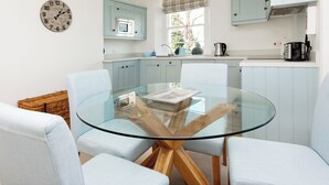 Een moderne keuken met lichtblauwe kastjes, een glazen eettafel en een houten salontafel.