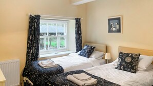 A double room with two beds, a window with curtains, a radiator, and a framed picture on the wall. - 3 bedroom accommodation in Rudston, near Bridlington (Rudston, near Bridlington)