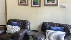 A living room with two leather sofas, each with a striped pillow, and a small round table. There are three framed artworks on the wall. - 3 bedroom accommodation in Rudston, near Bridlington (Rudston, near Bridlington)