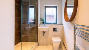 Ein modernes Badezimmer mit einer Duschkabine, einem Waschbecken, einer Toilette und einem Fenster.