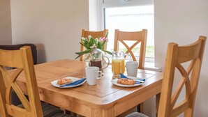 A wooden dining table with chairs, a coffee pot, a pitcher of juice, a mug, and two plates with pastries. - Gatekeepers Cottage - UK6728 (Lydstep, near Tenby)