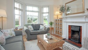 A living room with a fireplace, a sofa, a coffee table, and a bookshelf. - 3 bedroom accommodation in Lympstone (Lympstone)
