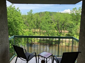 A balcony with a view of a river and forest.