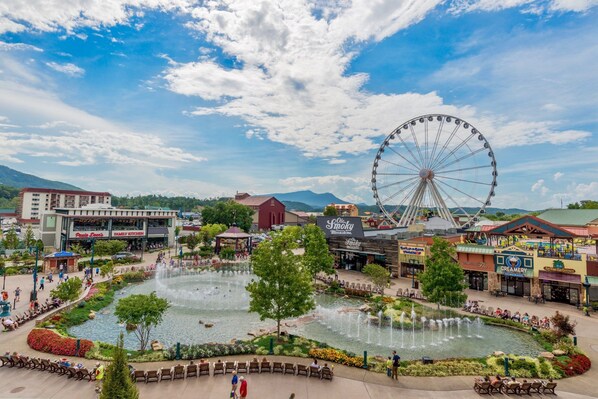 A large outdoor plaza with a fountain, a Ferris wheel, and various shops and restaurants.