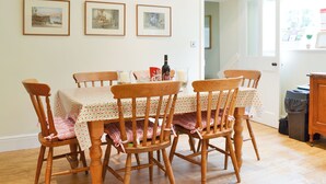A dining area with a table set for four, wooden chairs, and six framed pictures on the wall. - 3 bedroom accommodation in Rudston, near Bridlington (Rudston, near Bridlington)