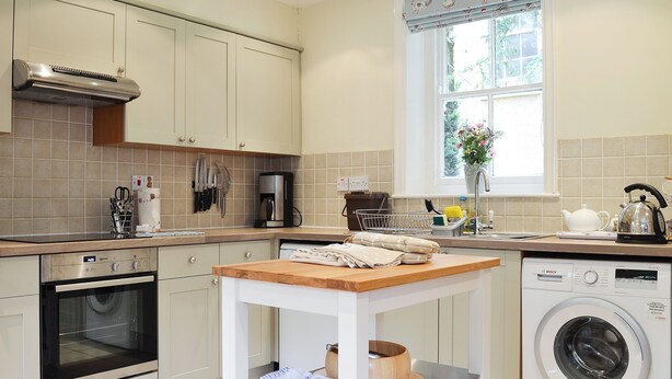 A kitchen with a built-in oven, a coffee maker, a kettle, and a washing machine. - 3 bedroom accommodation in Rudston, near Bridlington (Rudston, near Bridlington)